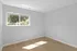 Bright and airy room with large window, showcasing natural light and a serene view of lush greenery.