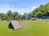 Vibrant dog park with agility equipment, lush green grass, and serene surroundings.
