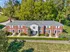 Charming brick townhouse complex nestled against lush greenery, featuring classic architecture and manicured landscaping.