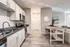 Modern kitchen with sleek white cabinetry, stainless steel appliances, and elegant granite countertops, flowing into a cozy living area with natural light.