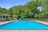 Inviting outdoor pool area surrounded by lush greenery, featuring comfortable lounge chairs and vibrant sun umbrellas for relaxation.