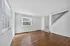 Bright and inviting living area with elegant hardwood floors and crisp white walls featuring a charming staircase, perfect for modern living.