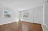 Bright, sunlit room with elegant hardwood flooring and crisp white walls, perfect for a welcoming entryway or cozy living space.