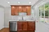 Charming kitchen with warm wooden cabinets, granite countertop, and herringbone backsplash, featuring a modern sink and stainless steel dishwasher.