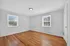 Bright and inviting room featuring polished hardwood floors and abundant natural light from dual windows.