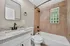 Elegant bathroom showcasing granite countertop sink, tiled walls, and a modern bathtub with a glass block window.