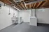 Spacious laundry room with modern washer and dryer, sleek concrete floor, and contemporary exposed-beam ceiling.