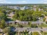 Vibrant aerial view of a leafy suburban neighborhood featuring charming brick townhouses, lush green spaces, and a backdrop of modern office buildings, offering a perfect blend of tranquility and urban convenience.