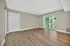 Bright and spacious living room with elegant wood flooring and large sliding glass doors leading to a balcony with scenic green views.