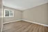 Bright and spacious empty room with elegant wood flooring and a large window, offering ample natural light.
