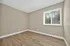 Sunlit room with elegant wood flooring and a large window, perfect for a cozy bedroom or stylish home office.