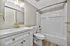 Elegant bathroom featuring gold fixtures, a sleek vanity, and a pristine shower-bathtub combination.