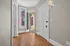 Bright entryway with rich hardwood floors, tall windows, and elegant lighting, leading to a charming outdoor view.