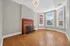 Inviting living room with elegant wooden floors, a classic brick fireplace, and large bay windows providing abundant natural light.