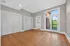 Bright and spacious room with elegant hardwood floors, ample closet space, and large windows leading to a scenic balcony view.