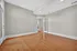 Bright empty room with hardwood flooring, elegant double doors, and abundant natural light.