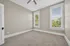Bright and airy empty room with neutral walls, large windows, and plush carpeting, ideal for personalization.