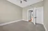 Inviting bedroom with plush carpeting, neutral tones, and a modern ceiling fan, leading to a sunlit hallway.