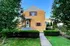 Charming brick house with a welcoming front porch, vibrant greenery, and a neatly trimmed pathway.