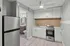 Modern kitchen with sleek stainless steel fridge, elegant white cabinets, and cozy adjacent bathroom, perfect for compact living.