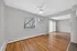 Bright and spacious living area featuring elegant hardwood floors, large window with a view, and a ceiling fan for comfortable living.