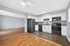 Modern open kitchen with sleek black appliances, spacious countertops, and ample natural light leading into a bright, airy living area with elegant hardwood flooring.