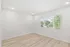 Bright and airy room with modern flooring and large window offering scenic views of lush greenery.