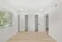 Bright and spacious bedroom with large window, showcasing natural light, sleek wood flooring, and ample closet storage.