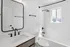 Bright and elegant bathroom with modern fixtures, featuring a sleek vanity, large mirror, and luxurious rainfall shower.