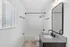 Bright and modern bathroom featuring a chic vanity with a spacious sink, elegant fixtures, and a pristine shower area with sleek tiles.