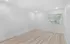 Bright, airy room with elegant wood flooring and large window for natural light.