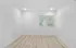 Bright minimalistic room with light wood flooring and a large window highlighting modern blinds.