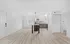 Sleek modern kitchen with stainless steel appliances, pendant lighting, and elegant light wood flooring in a spacious open-concept living area.