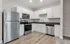 Modern kitchen with sleek stainless steel appliances, elegant white cabinetry, and stylish wood flooring.