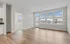 Bright, modern apartment with open-floor living area, elegant hardwood floors, and expansive windows offering natural light and picturesque views.