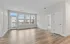 Bright and spacious living area with modern flooring and large windows offering natural light and a view of the balcony.