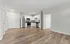 Modern open-plan apartment with sleek wood flooring, bright kitchen featuring stainless steel appliances, and spacious living area.