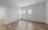 Bright and airy room with modern hardwood floors, large windows, and a door leading to a sunny balcony, perfect for relaxing or entertaining.
