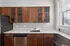 Elegant kitchen with rich wooden cabinetry, sleek countertops, and ample natural light from large windows, creating a warm and inviting space. Clermont Condominiums apartments in East Walnut Hills, Cincinnati, OH.