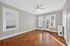 Bright and inviting living room with elegant hardwood floors, a ceiling fan, and charming glass doors leading to a cozy balcony.