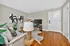 Inviting living room with stylish decor, featuring a cozy white sofa, abstract art, wooden flooring, and a modern television setup.