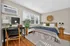Bright and cozy bedroom with a modern desk and chair, stylish decor, and ample natural light from large windows.