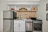 Modern kitchenette with sleek stainless steel appliances, elegant white cabinetry, and open shelving for a stylish, functional space.