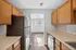 Bright, modern kitchen with stainless steel appliances, subway tile backsplash, and warm wood cabinetry leading into a sunlit dining area.