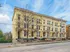 Charming Victorian-style yellow apartment building with ornate porches and decorative details against a bright blue sky.