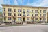 Charming yellow apartment building with intricate architectural details and lush landscaping, promising comfortable urban living.