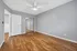Bright and airy bedroom with sleek hardwood floors, modern ceiling fan, and spacious mirrored closet in a serene gray color palette.
