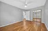 Bright and spacious bedroom with sleek hardwood floors, neutral gray walls, mirrored closet doors, and a modern ceiling fan.