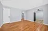 Bright and airy apartment showcasing elegant hardwood floors, neutral gray walls, and a ceiling fan, seamlessly connecting to the adjacent kitchen or dining area.