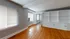 Bright and inviting room with polished hardwood floors, large windows with blinds, and built-in white shelving offering ample storage space.